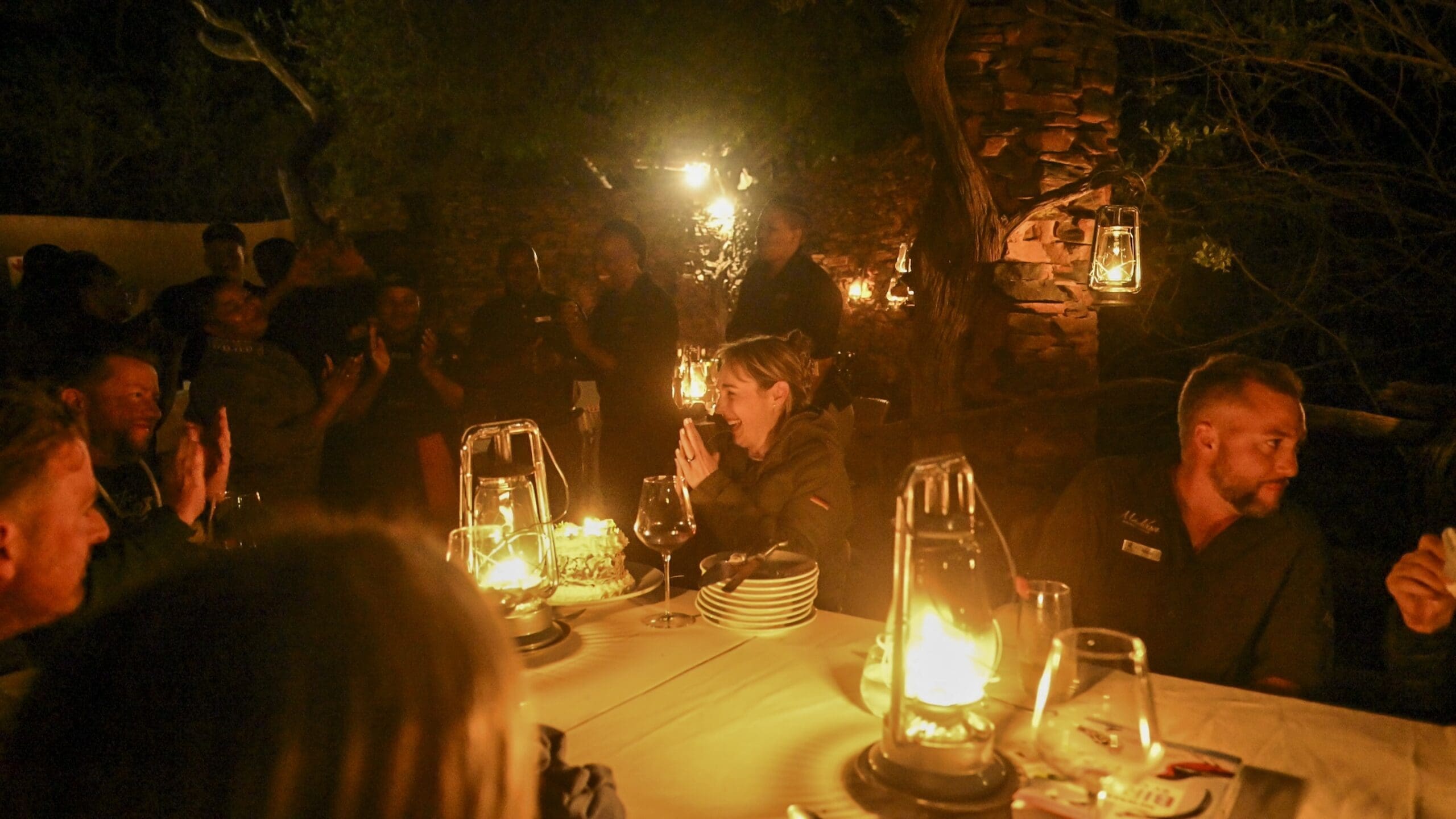 Guests enjoying a candlelit boma dinner at Madikwe Safari Lodge, sharing food, laughter, and conversation under the African night sky.